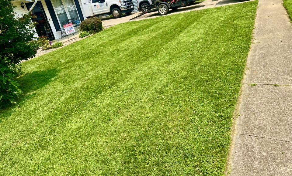 Front lawn with faint stripes, the truck parked in the drive