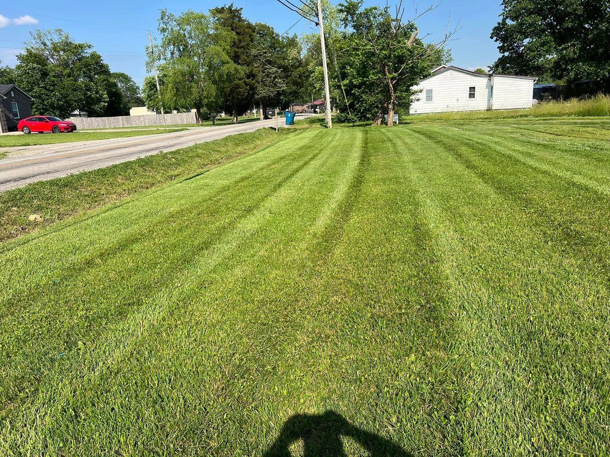 Long striped strip of mowed grass running out to the road under a big sky